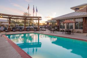 ein Pool mit Tischen und Stühlen und ein Gebäude in der Unterkunft Hilton Garden Inn Yuma Pivot Point in Yuma