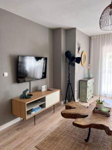uma sala de estar com uma televisão de ecrã plano na parede em Suite Bonalba em Alicante