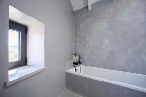 a white bathroom with a window and a bath tub at Casa na Curva - Artists Corner Country house in Lagos