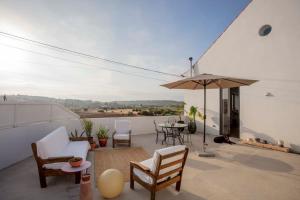 een patio met een tafel en stoelen en een parasol bij Casa na Curva - Artists Corner Country house in Lagos