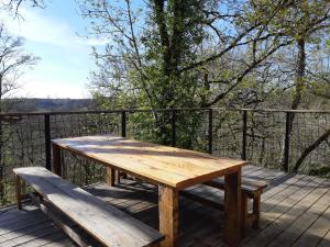 a wooden table and benches on a wooden deck at Gîte avec spa privatif et piscine de 2 à 10 voyageurs in Brassac