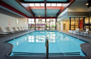 una gran piscina con sillas y mesas en un edificio en DoubleTree by Hilton Boston/Westborough en Westborough