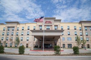 a hotel with an american flag in front of it at Hampton Inn and Suites by Hilton McKinney in McKinney