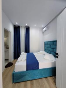 une chambre avec un grand lit et une tête de lit bleue dans l'établissement Vasilika apartament, à Saranda