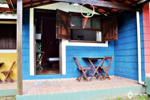 una casa azul con 2 sillas y una mesa en Eco Chalés Luar das Marés en Ubatuba