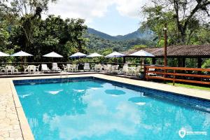 a large swimming pool with chairs and umbrellas at Eco Chalés Luar das Marés in Ubatuba