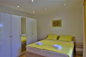 a bedroom with a bed with yellow sheets and towels at Apartments Fabijanić in Rab