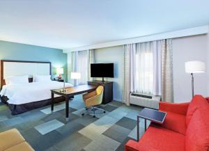 ヒューストンにあるHampton Inn & Suites Houston North IAH, TXのベッドと赤いソファが備わるホテルルームです。