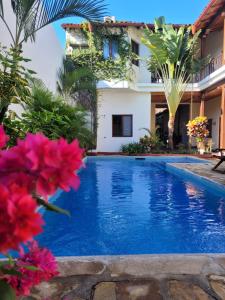 une piscine en face d'une maison ornée de fleurs roses dans l'établissement Hotel con Corazón, à Granada