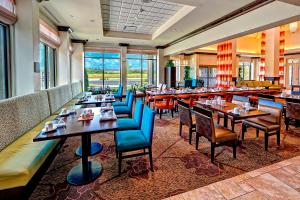 um restaurante com mesas, cadeiras azuis e janelas em Hilton Garden Inn Memphis/Wolfchase Galleria em Memphis