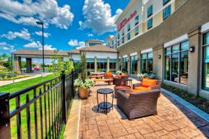 Hilton Garden Inn Memphis/Wolfchase Galleria في ممفيس: فناء به كنب وطاولات خارج الفندق