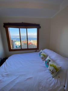 łóżko z 2 poduszkami w pokoju z oknem w obiekcie Oasis en Cerro Alegre w mieście Valparaíso