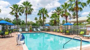 einen Pool mit Stühlen und Sonnenschirmen in einem Resort in der Unterkunft Hilton Garden Inn Orlando East - UCF Area in Orlando