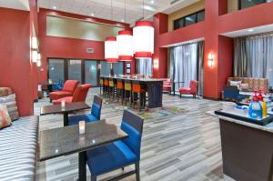a hotel lobby with red walls and tables and chairs at Hampton Inn and Suites Pauls Valley in Pauls Valley