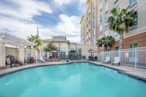 a swimming pool in a hotel with tables and chairs at Hilton Garden Inn San Antonio/Rim Pass Drive in San Antonio