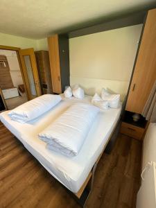 ein großes Bett mit weißer Bettwäsche und Kissen darauf in der Unterkunft Apart Bader in Ehrwald