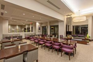 un restaurante con mesas de madera y sillas moradas en Hilton Garden Inn Irvine/Orange County Airport, en Irvine