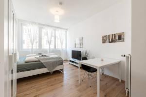 a white bedroom with a bed and a desk at Stilvolle Wohnung zentral Bremen in Bremen