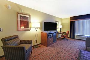 Hampton Inn & Suites Milwaukee/Franklin في فرانكلين: غرفة في الفندق مع تلفزيون وأريكة وكرسي