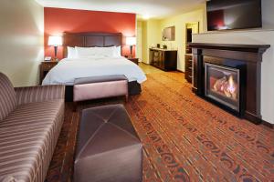 a hotel room with a bed and a fireplace at Hampton Inn & Suites Milwaukee/Franklin in Franklin