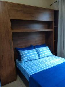 a bed with a wooden headboard and two blue pillows at Loft Aconchegante no Centro de Niterói!! in Niterói
