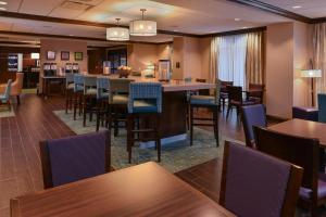 a restaurant with tables and chairs and a bar at Hampton Inn Omaha Midtown-Aksarben in Omaha