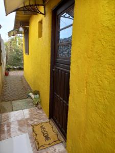 una puerta amarilla con una alfombra de bienvenida delante de ella en Habitación Independiente, en Chuy
