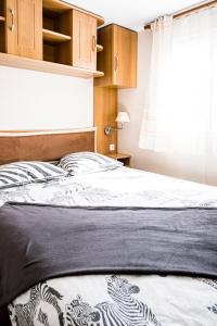 een bed met een zwart-witte sprei en een raam bij mobil home in Hyères