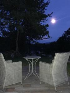 two chairs and a table in a yard at night at River House Moon in Gospić