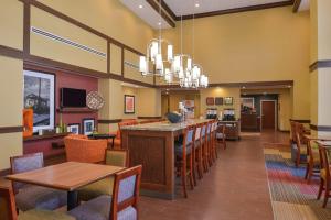 a restaurant with a bar and tables and chairs at Hampton Inn & Suites by Hilton Lonoke in Lonoke