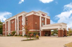 un grand bâtiment en briques rouges avec un parking dans l'établissement Hampton Inn Hernando, MS, à Hernando