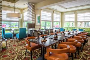 a dining room with tables and chairs and windows at Hilton Garden Inn Bettendorf/ Quad Cities in Bettendorf