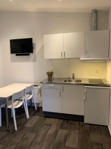 una cocina con armarios blancos y una mesa con sillas. en Vorbasse Holiday Apartments, en Vorbasse