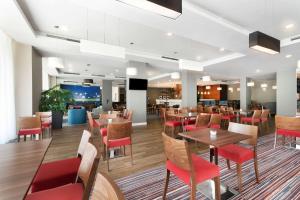 a restaurant with wooden tables and red chairs at Hampton by Hilton Krakow in Krakow