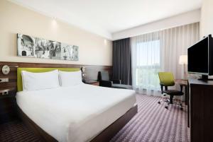 a hotel room with a bed and a desk and a television at Hampton by Hilton Krakow in Krakow