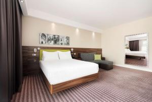 a hotel room with a bed and a chair at Hampton by Hilton Krakow in Kraków +30 photos