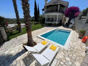 a swimming pool with two chairs and a house at Casa StaLa in Kastanéa