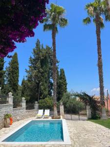 a swimming pool with two chairs and palm trees at Casa StaLa in Kastanéa