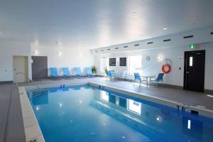 - une grande piscine dans un bâtiment avec des chaises bleues dans l'établissement Hampton Inn Saskatoon South, à Saskatoon