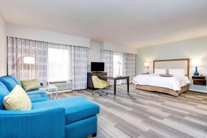 a hotel room with a bed and a blue couch at Hampton Inn Macon - I-475 in Macon