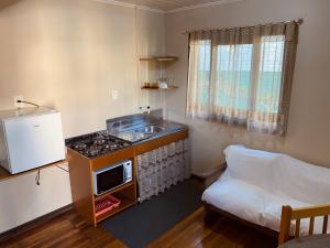 cocina con fogones, fregadero y cama en Residenciais Maria Flor, en Gramado