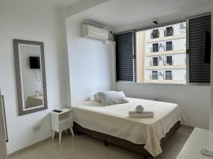 a white bedroom with a bed and a mirror at Frente Mar! 3 quartos e 2 vagas in Santos