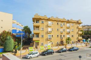 un gran edificio amarillo con coches estacionados frente a él en 244 Cabo Roig Luxury -Alicante Holiday, en Cabo Roig
