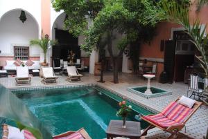 - une piscine avec des chaises longues et une table dans l'établissement Riad Barroko, à Marrakech