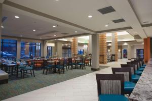 a dining room with tables and chairs and windows at Hilton Garden Inn Bolingbrook I-55 in Bolingbrook