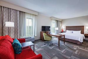 Habitación de hotel con cama y sofá rojo en Hampton Inn & Suites Claremore, en Claremore