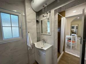 Baño blanco con lavabo y espejo en Sunčana Kula en Herceg-Novi
