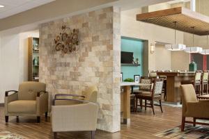 un vestíbulo con una pared de piedra con sillas y un bar en Hampton Inn & Suites Minooka, en Channahon