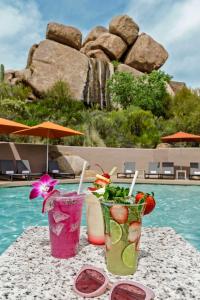 斯科茨代爾的住宿－Boulders Resort & Spa Scottsdale, Curio Collection by Hilton，坐在泳池旁的桌子上,喝上两杯鸡尾酒