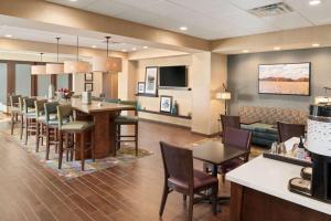 a restaurant with a bar and a dining room at Hampton Inn Lincoln Airport, Ne in Lincoln